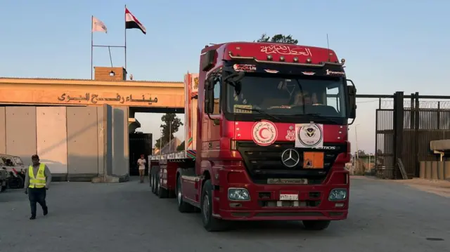 A large red truck drives through a concrete gate