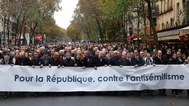 A crowd of protesters gathered in Paris, many of them holding up a banner opposing antisemitism