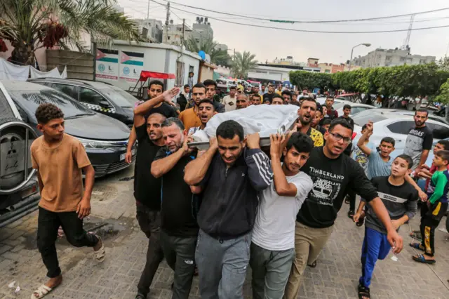 Men mourn as they carry a body to be buried