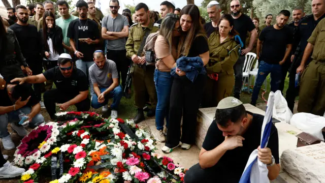 Two women hug at the graveside of Sergey Shmerkin