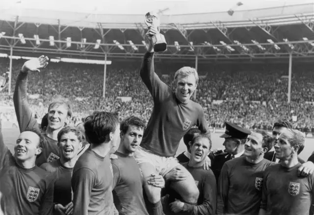 Bobby Charlton looks up at England captain Bobby Moore