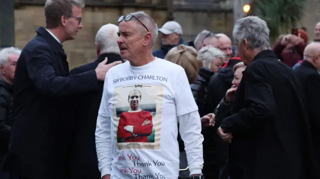 Fan with an image displayed of Bobby Charlton on his shirt after his funeral