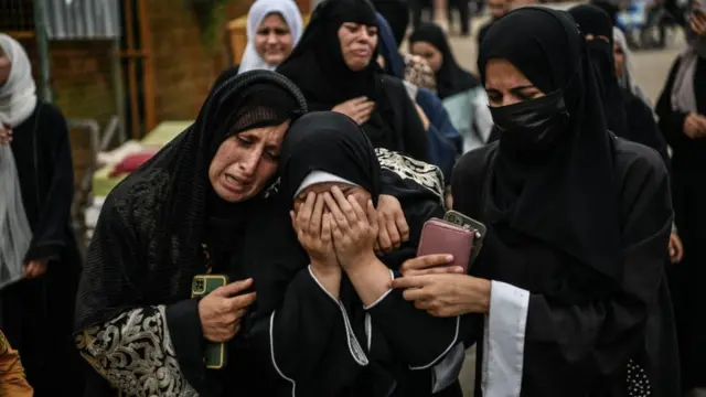 Relatives of the people killed in Israeli attacks mourn as the bodies are taken to Nasser Hospital's morgue a