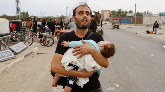 A Palestinian man holding a child flees northern Gaza