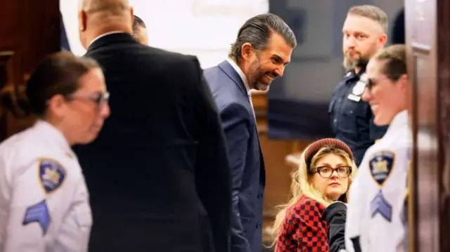 Donald Trump Jr stops to look at a courtroom sketch as he returns from a break