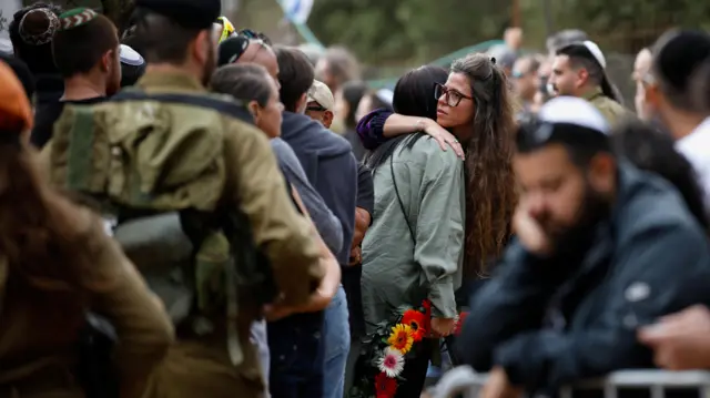 People hug at the funeral of Matan Meir