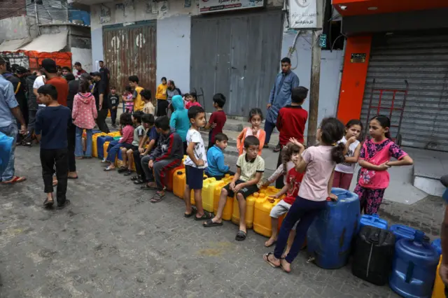 Palestinians, including children, waiting to get clean water from mobile tanks