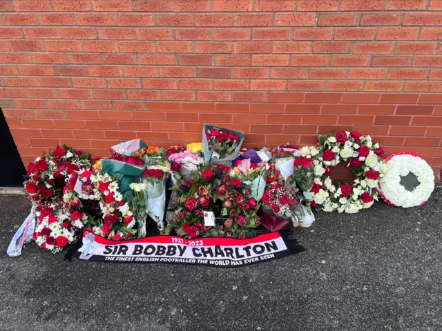 Floral tributes and a scarf left in honour of Sir Bobby Charlton