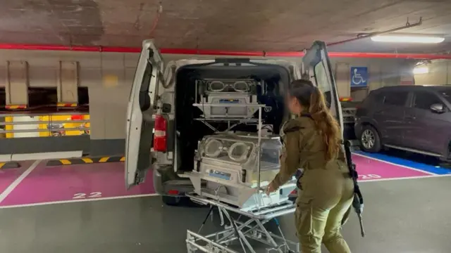 An IDF soldier unloads an incubator from a van in a car park