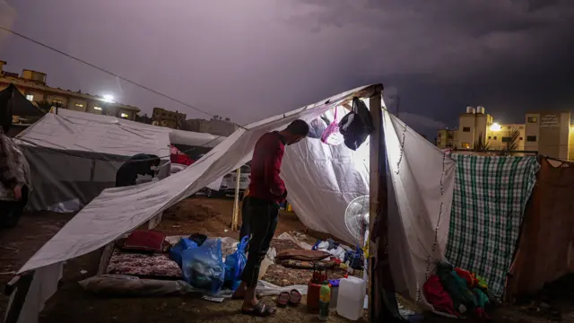 A man standing under a makeshift tent in Khan Younis