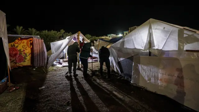 Men stand under makeshift tents