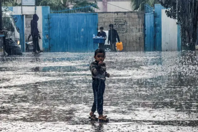 A boy stands in the rain in Rafah in the southern Gaza Strip