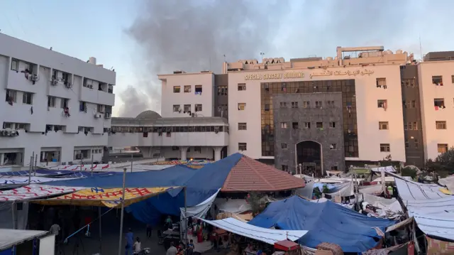 Smoke rises as displaced Palestinians take shelter at Al Shifa hospital, amid the ongoing conflict between Hamas and Israel, in Gaza City,