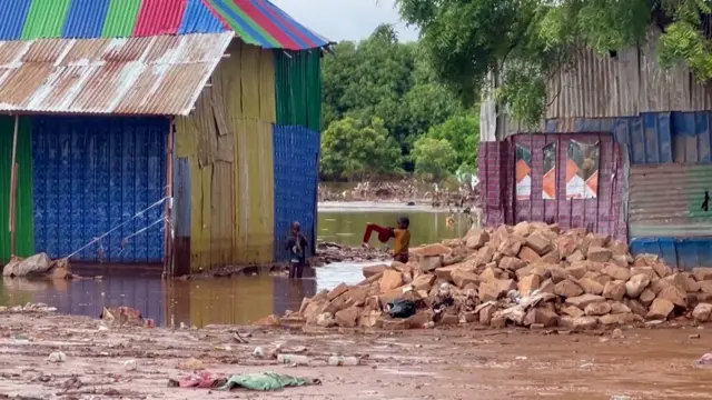 Two children in the middle of destroyed houses surrounded by water