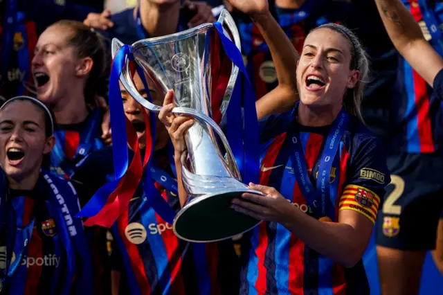 Putellas holds the UWCL trophy in front of her teammates.