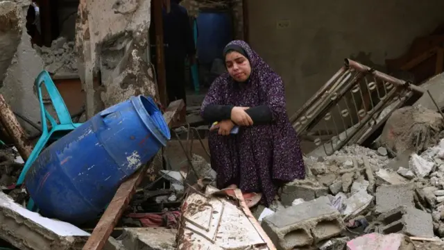 A woman sits amongst rubble