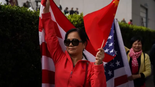 A woman walks with the national flags of the US and China in San Francisco