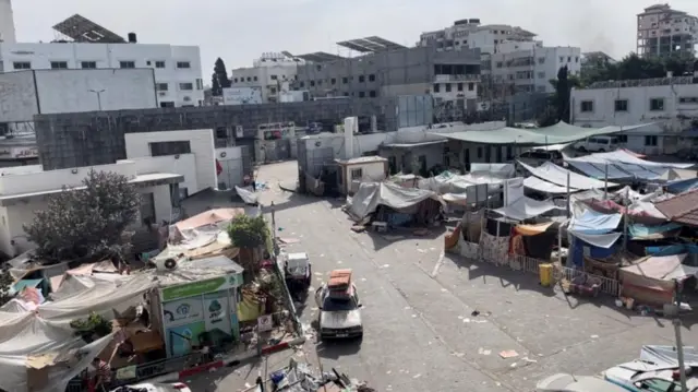 A wide view of tents and makeshift shelters on the concrete ground of a medical campus