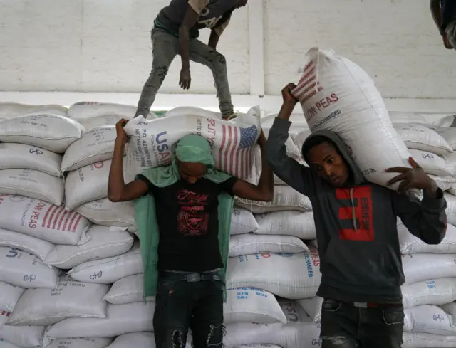 Aid workers move bags of yellow lentils that are part of athree-piece "Full Package" to be distributed to residents of Geha subcity at an aid operation run by USAID, Catholic Relief Services and the Relief Society of Tigray on June 16, 2021 in Mekele, Ethiopia.