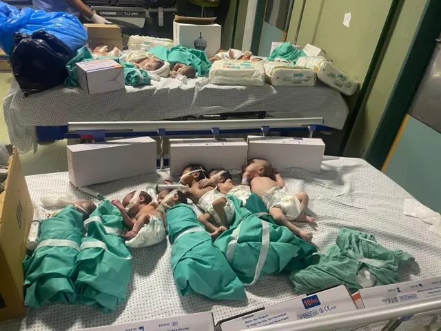 Several newborn babies placed on two beds inside a hospital