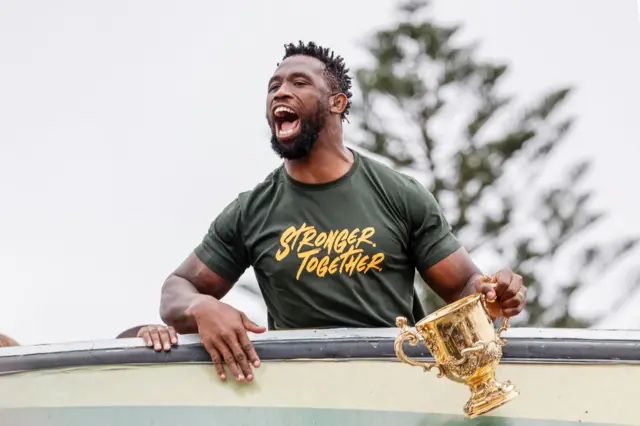 South Africa's flanker and captain Siya Kolisi reacts as he holds the throphy from the bus carrying the rest of the team during the Springboks Champions trophy tour in East London, South Africa, on November 5, 2023, after South Africa won the France 2023 Rugby World Cup final match against New Zealand