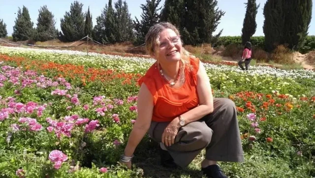 Yehudit Weiss crouching in a field of flowers