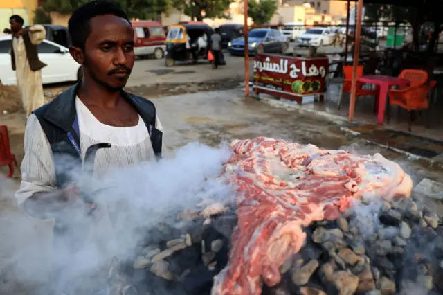 A chef barbeques meat on stones heated on layers of embers placed in a large metal container as he prepares a traditional dish of the Beja tribes at an open air cafe in the Diem Medina district in the center of Port Sudan, the capital of the Red Sea State in eastern Sudan, on November 14