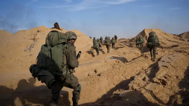 Soldiers working through sandy hills in full gear