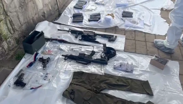 A view of the weapons and uniforms found by police in the gunmen's vehicle, sprawled out on the ground on a white plastic sheet