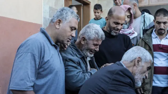 Men huddle together while mourning death of loved ones