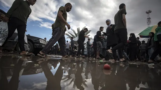 Palestinians walking through muddy water in Khan Younis, southern Gaza