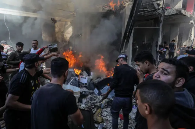 Residents try to save survivors amid fire and debris following an air strike