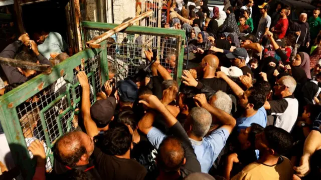 A crowd surges towards a shopfront