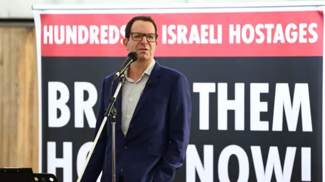 Naom Sagi, son of Ada Sagi, speaks to people viewing the empty places laid out for the 220 hostages at a 'Shabbat' table in London on 27 October 2023