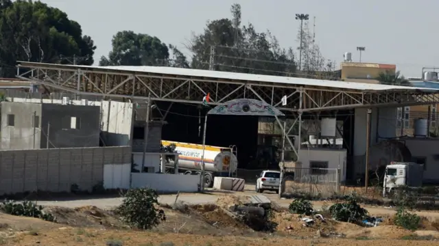 The back-half of a fuel tanker can be seen inside the gates of a border crossing