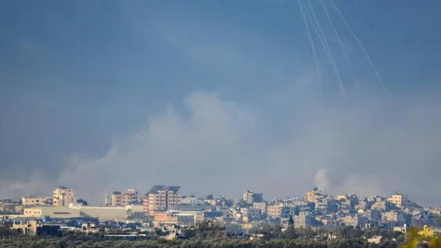 Five smoke trails are visible in blue sky as missiles approach Gaza from above