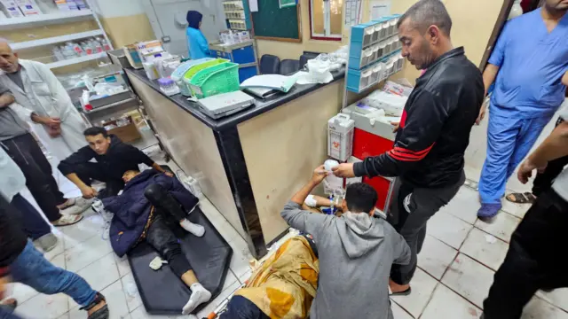 Wounded people lie on the floor of a hospital, receiving treatment