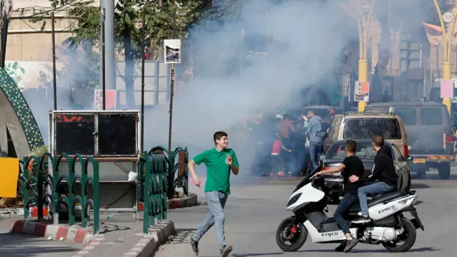 Palestinians run for cover from tear gas dropped by an Israeli drone during a protest in support of the people of Gaza