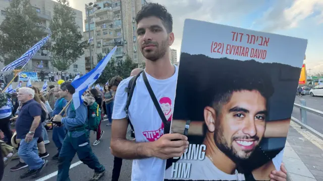 Man holds a photo of his missing brother, taken hostage by Hamas