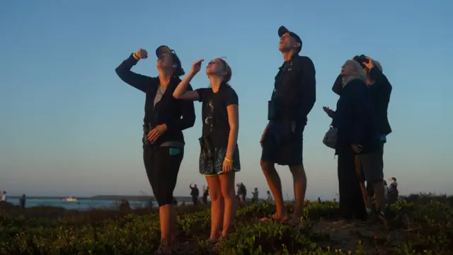 People watch as SpaceX's next-generation Starship spacecraft lifts off from the company's Boca Chica launchpad