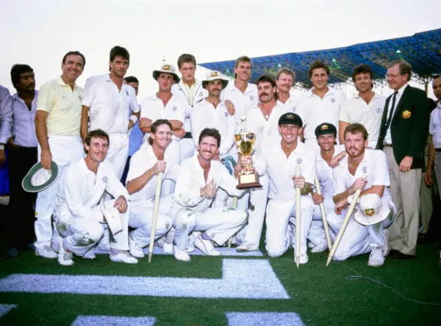 Australia captain Allan Border holds the trophy with Geoff Marsh (r) as the rest of the team and management celebrate after Australia had beaten England by 7 runs to win the 1987 Cricket World Cup in Calcutta, India.