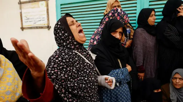 A woman looks to the sky, wailing in grief