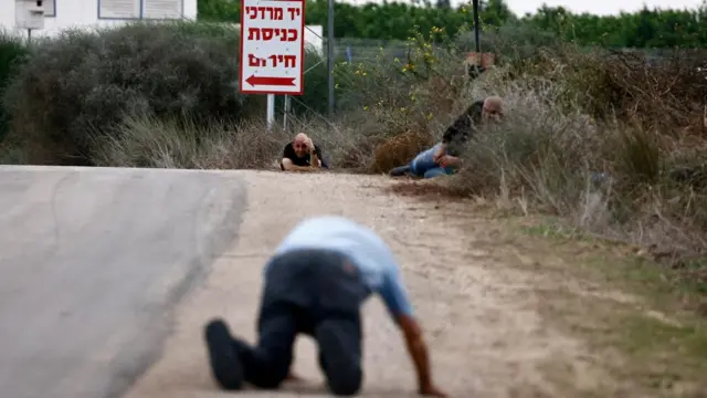 Three men lie on the side of a road among grass