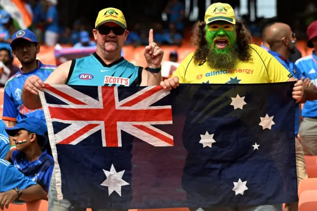 Fans hold national flag as they cheer for Australian team before the start of the 2023 ICC Men's Cricket World Cup one-day international (ODI) final match between India and Australia at the Narendra Modi Stadium in Ahmedabad on November 19, 2023.