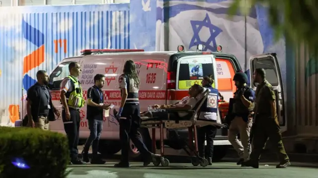 A man lies on a stretcher as ambulance workers load him into the vehicle