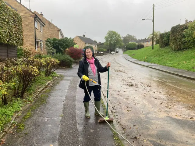 Mrs Hurford cleaning the road outside her house