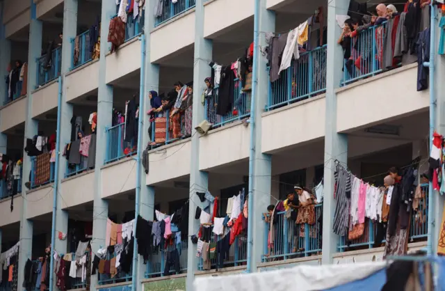 Palestinians, who have fled their homes due to Israeli strikes, watch a nearby Israeli strike as they take shelter in a UN-run school, in Khan Younis in the southern Gaza Strip, October 27, 2023