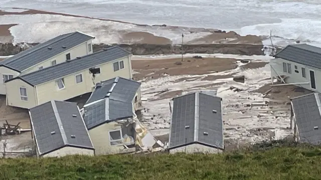 Caravans sit scattered on a beach with bits of debris in between