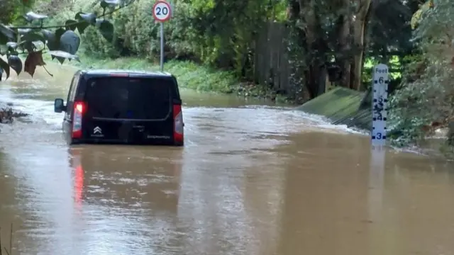 A black van is stranded in flood water