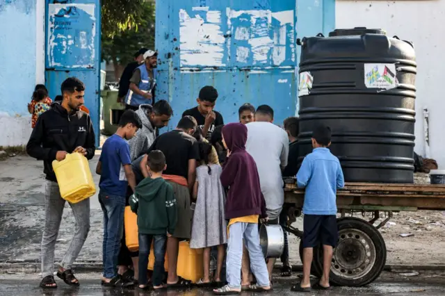 Gaza residents lining up at a portable cistern to collect water